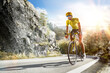 © 103tnn - Cycling. A captivating shot of a helmeted biker riding along an asphalt road, demonstrating the freedom and excitement of road riding. Cycling competitions. Active recreation. Sport.