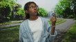 © Krakenimages.com - African american woman with braided hair and glasses gives thumbs down gesture on a tree lined park walkway; disapproval.