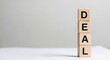 © Yameen - Wooden blocks stacked vertically spell out the word deal against a neutral background ideal for business and negotiation concepts