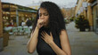 © Krakenimages.com - Woman coughing outdoors on a terrace with a blurred street background