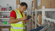© Krakenimages.com - Young man in charity center organizing donations wearing high-visibility vest using tablet focusing on logged items for distribution and management