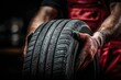 © Alexander LW - Hands of a mechanic holding a new tire on a black background with space for text