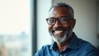 © Viktor - Smiling African American man with grey beard and glasses wears blue shirt indoors near window. He looks successful and confident in his mid-fifties, radiating professionalism and warmth.