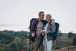 © sashafolly - Mature man wraps arm around woman and smiles holding trekking poles