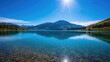 © vxnaghiyev - View of a pristine mountain lake reflecting blue skies, seasonal change