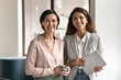 © fizkes - Smiling diverse businesswomen colleagues standing in office looking at camera