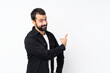 © luismolinero - Young man with beard over isolated white background pointing back