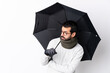 © luismolinero - Caucasian handsome man with beard holding an umbrella over isolated white wall portrait