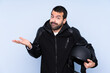 © luismolinero - Man with a motorcycle helmet over isolated background making doubts gesture