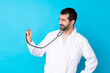 © luismolinero - Young caucasian man over isolated background wearing a doctor gown and with stethoscope