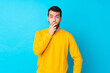 © luismolinero - Young caucasian man over isolated blue background surprised and shocked while looking right