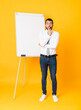 © luismolinero - Full-length shot of businessman giving a presentation on white board over isolated yellow background surprised and shocked while looking right