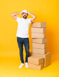 © luismolinero - Full-length shot of delivery man among boxes over isolated yellow background frustrated and takes hands on head
