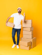 © luismolinero - Full-length shot of delivery man among boxes over isolated yellow background surprised and pointing up