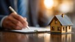 © AR - Businessman signing a contract to purchase a home with a house model on the table