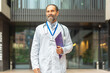 © Jelena - Experienced male doctor smiling carrying medical clipboard