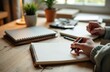 © starush - Person writing in a notebook on a wooden desk with office supplies and plants in the background