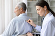 © Anastasiya - Female doctor in white coat examining senior male patients back with stethoscope during medical checkup in bright clinic office, professional healthcare service