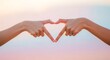 © Roushon - Two hands form a heart shape against a soft, pastelcolored sky, symbolizing love, connection, and unity in a peaceful and serene environment