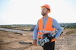 © Serhii - Engineer carrying surveying equipment at construction site
