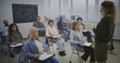 © Framestock - Diverse Adult Learners Sit Modern Desks, Writing and Listening Attentively Teacher. Class Remains Focused, Completing Assignments and Taking Notes During Structured Educational Sessions. Static Shot.
