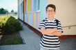 © Serhii - Smiling student standing with crossed arms in front of colorful school building