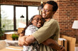 © DC Studio - African american couple sharing warm embrace in brick wall apartment, celebrating newly purchased home. Excited woman and boyfriend hug joyfully in cozy living room during moving day.