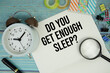 © may1985 - Do You Get Enough Sleep? text on a paper surrounded by office supplies, a magnifying glass, and a clock on a blue wooden surface
