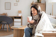 © Pixel-Shot - Young woman with warm plaid and cup of coffee at home on winter day