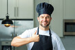 © Volodymyr - Happy chef cook with thumb up. Portrait of chef, cooks or baker. Man in cook hat and chef uniform cooking on kitchen.