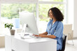 © Pixel-Shot - Female African-American medical student using computer at table in office