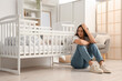 © Pixel-Shot - Young mother with her baby in crib suffering from postnatal depression at home