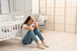 © Pixel-Shot - Young mother with her baby in crib suffering from postnatal depression at home