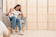 © Pixel-Shot - Young mother with her baby suffering from postnatal depression in armchair at home