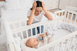 © Pixel-Shot - Young mother with her baby in crib suffering from postnatal depression at home