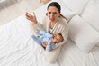 © Pixel-Shot - Young mother with her baby suffering from postnatal depression in bedroom, top view