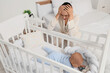 © Pixel-Shot - Young woman with her baby in crib suffering from postnatal depression at home