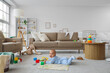 © Pixel-Shot - Cute little baby with toys lying on carpet in living room