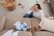 © Pixel-Shot - Young mother suffering from postnatal depression and her baby on sofa at home, top view
