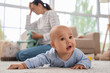 © Pixel-Shot - Little baby on carpet against mother suffering from postnatal depression at home, closeup