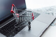 © vladdeep - Miniature Shopping Cart Rests On A Laptop Keyboard, With US Dollar Bills Scattered Nearby