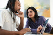 © Studio Marmellata - Diverse colleagues collaborate on a project. A man works on his laptop while a woman listens attentively, holding a pen. They are focused on their tasks.
