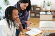 © Studio Marmellata - Diverse colleagues collaborate on a project. A woman points to a notebook while a man with dreadlocks listens intently at a desk with a laptop.