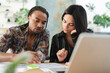 © Studio Marmellata - A diverse man and woman collaborate at a desk, reviewing documents and a laptop. They are engaged in a focused discussion, working together on a shared project.