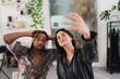 © Studio Marmellata - A diverse young couple takes a selfie together with a smartphone. The woman holds the phone while the man poses with his hands behind his head. They are smiling indoors.