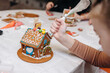 © Katrin_Primak - Children happily decorating gingerbread houses with icing and candy for a festive Christmas holiday activity