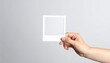 © akhmad - A hand holding a white photo frame against a neutral background emphasizing simplicity