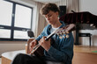 © Halfpoint - Teenage boy playing acoustic guitar in school music room.