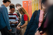 © Halfpoint - Teen students hanging out in school hallway by lockers.
