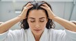 © Vasiliy - Woman massaging her scalp with her eyes closed. Brunette applying hair care treatment or shampoo for healthy hair growth. Self-care and beauty routine in the bathroom